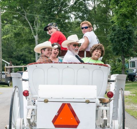 Guests in cowboy hats riding the park's white horse-drawn carriage