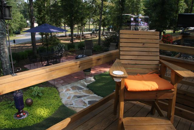 A wooden deck with an Adirondack chair looking over a landscaped lot