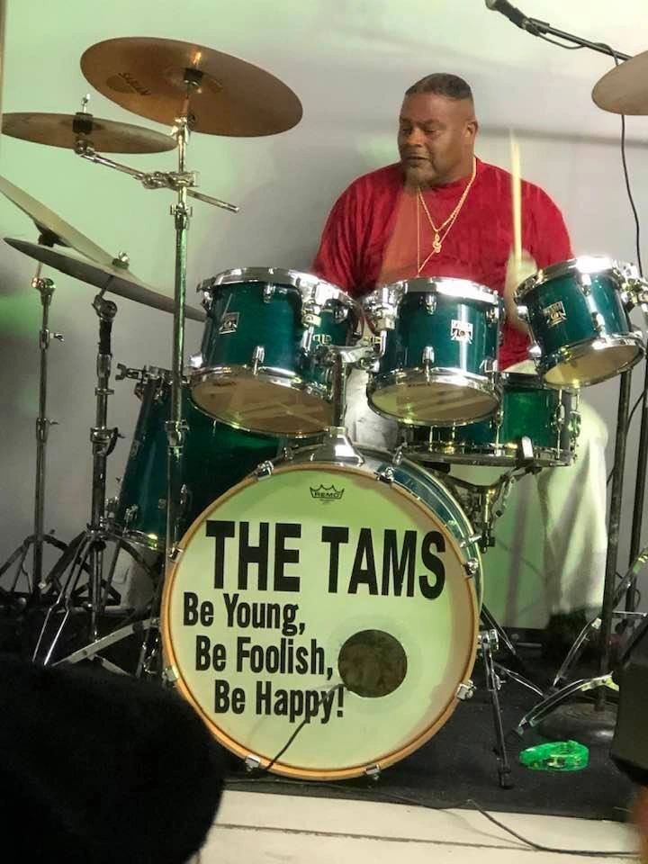 A drummer playing a live set on the stage at the park